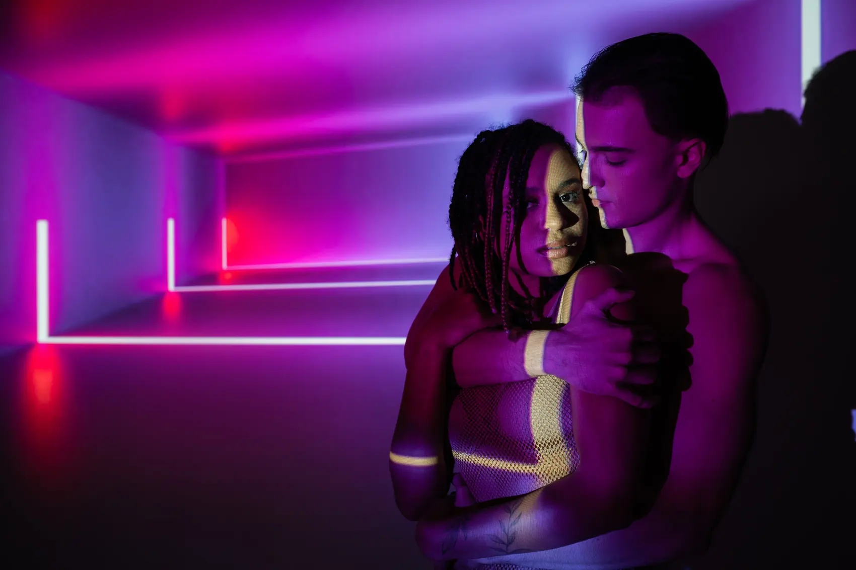 Couple in a vivid violet and pink neon-lit room